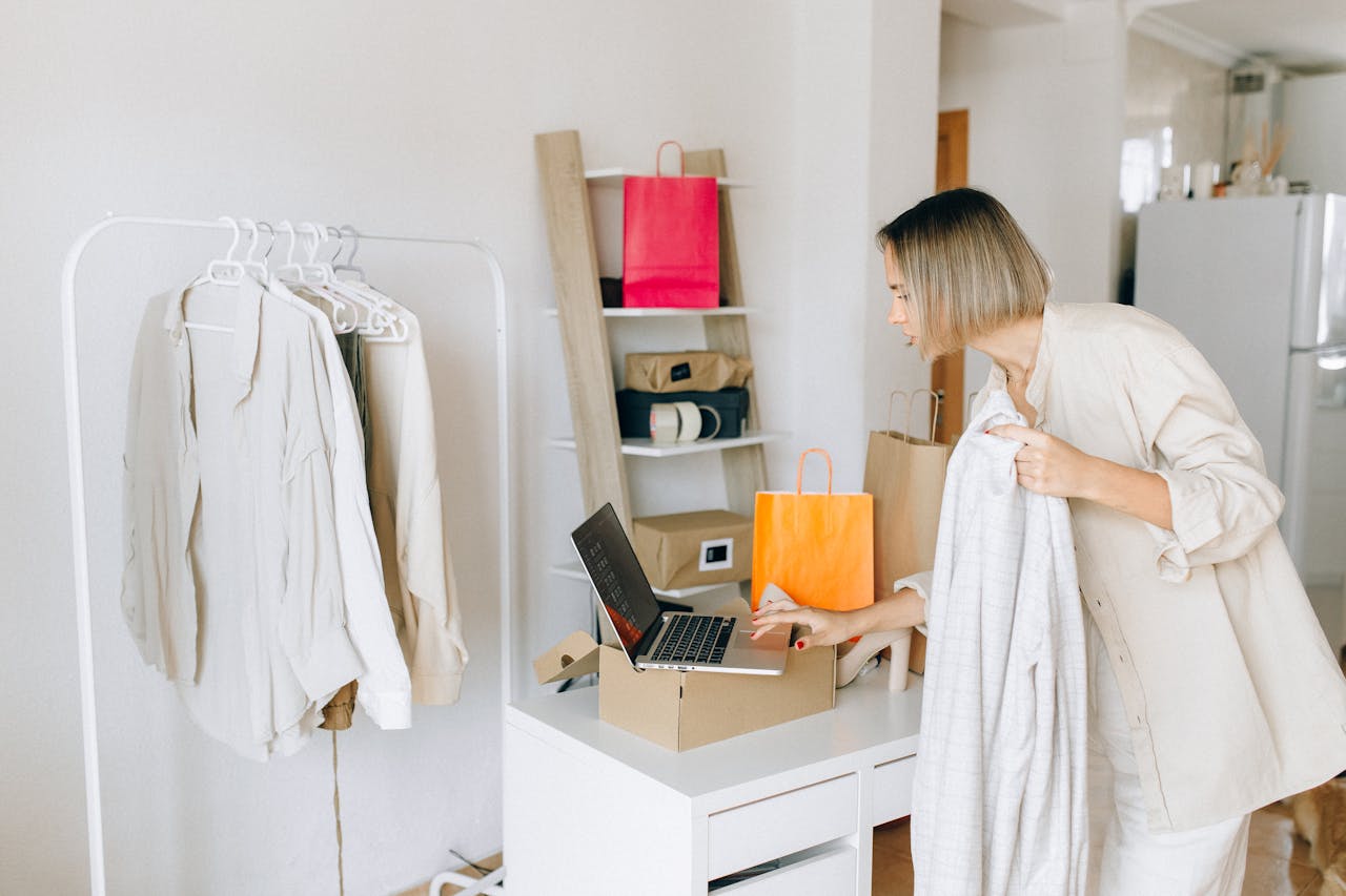 why-choose-us A woman in casual attire unpacking a delivery box with clothing at home, engaging in online shopping.